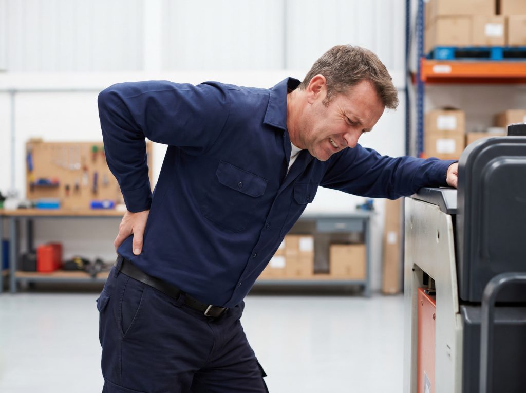 Man experiencing work-related back injury and physical strain during warehouse work