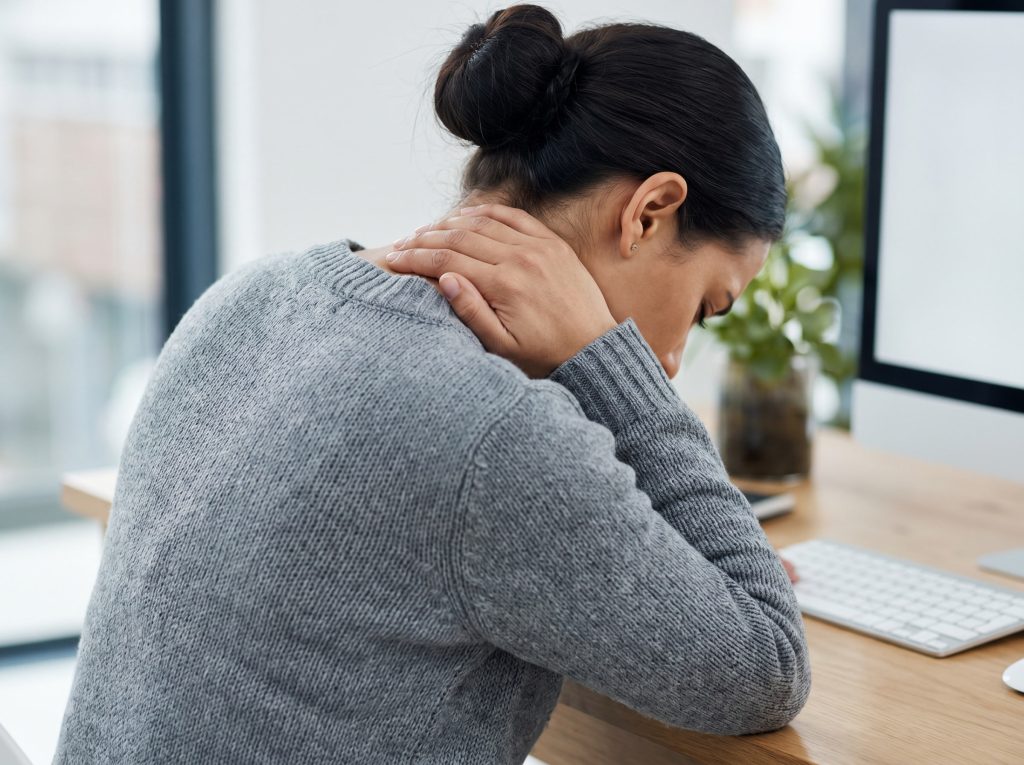 Woman experiencing neck and shoulder tension from desk work and poor posture in New Paltz NY