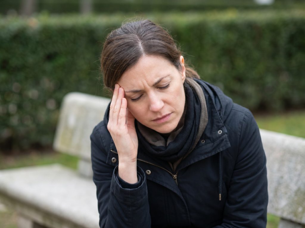 Woman experiencing headache and jaw tension discomfort outdoors in Hudson Valley NY